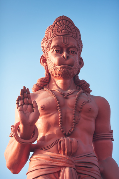 Blick von unten auf eine riesige Statue aus rotem Hanuman mit erhobener Hand in Segensgeste. - Foto, Bild