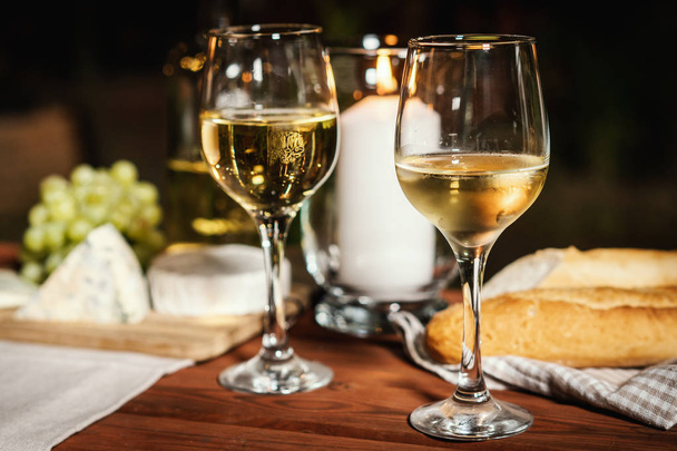cena romántica con dos copas de vino, una baguette y aperitivos en una vieja mesa de madera en una noche de verano
 - Foto, imagen