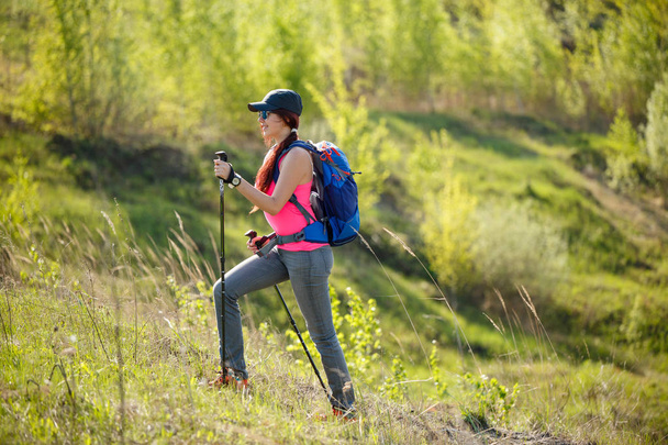 Photo of smiling sportswoman with walking sticks and backpack - Photo, Image