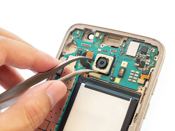 Gros plan de la caméra arrière de serrage de la main du technicien à l'intérieur du smartphone démonté cassé
 - Photo, image