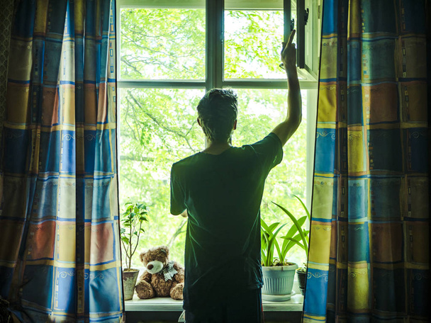 man standing in the bedroom opening window leaf - 写真・画像