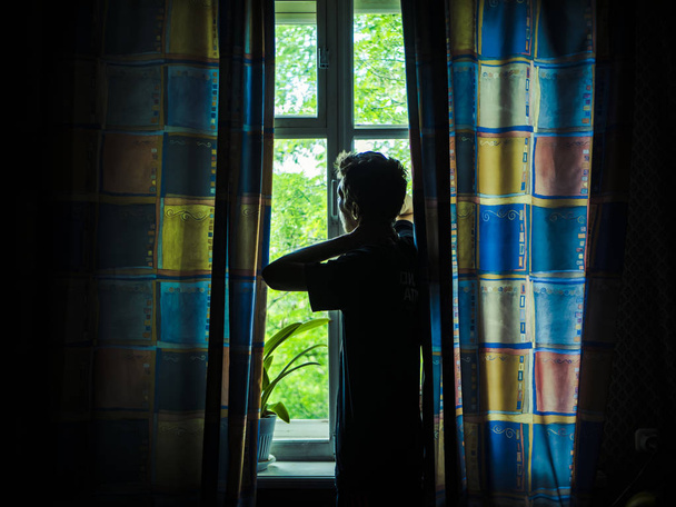 solo hombre silueta mirando a la ventana cerrada con cortinas en el dormitorio
 - Foto, imagen