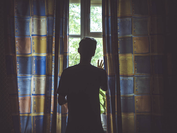 alone man silhouette staring at the window closed with curtains in bedroom - Fotoğraf, Görsel