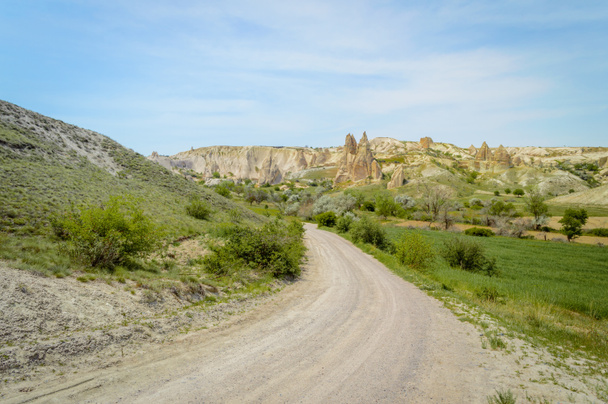front view of road in valley and mountains under cloudy blue sky, Cappadocia, Turkey  - Photo, Image