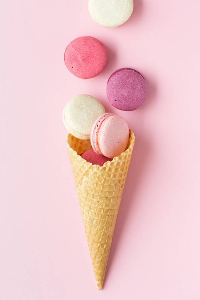Flatlay of pastel cake macaron or macaroon and sweet cones over pastel pink background. Top view with space for your text - Photo, image