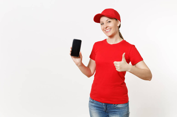 Παράδοση γυναίκα με κόκκινη στολή που απομονώνονται σε λευκό φόντο. Γυναίκα με καπέλο, μπλουζάκι, τζιν εργάζεται ως κούριερ ή έμπορος δείχνει την κάμερα κινητού τηλεφώνου με κενή κενή οθόνη. Διαφήμιση χώρο αντίγραφο - Φωτογραφία, εικόνα