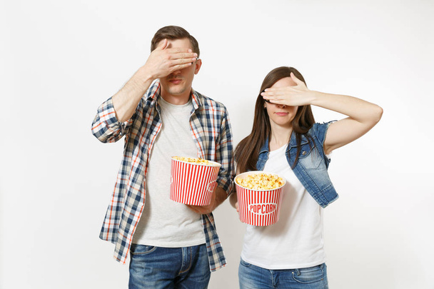 Fiatal elégedetlen pár, nő és férfi 3D-s szemüveg, néz film film napján, gazdaság pattogatott kukorica vödör, amely arcok a palm elszigetelt fehér background. Érzelmek a mozi koncepció - Fotó, kép