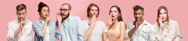 The young men and women whispering a secret behind hands over pink background - Photo, Image