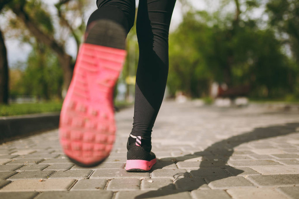 Обрезанные близко женские ноги в спортивной одежде, черные и розовые кроссовки, делающие спортивные упражнения, тренировки и бег трусцой на улице. Фитнес, концепция здорового образа жизни
 - Фото, изображение