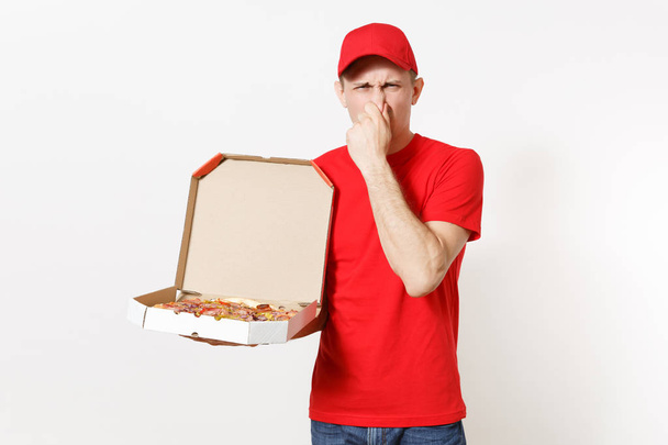 Delivery shocked man in red uniform isolated on white background. Male pizzaman in cap, t-shirt working as courier or dealer holding italian pizza in cardboard flatbox. Copy space for advertisement - Photo, Image