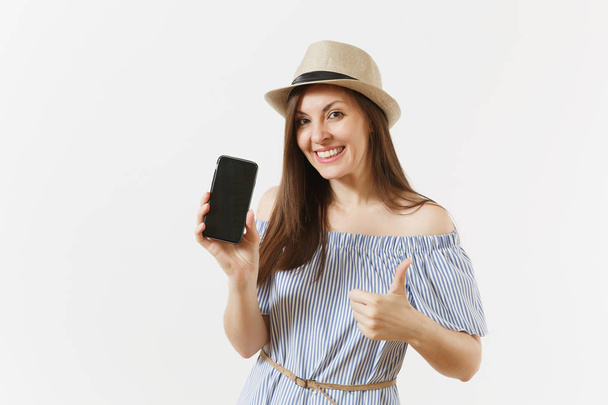 Jeune femme habillée robe bleue, chapeau montrant à l'appareil photo téléphone portable avec écran vide noir vierge isolé sur fond blanc. Les gens émotions sincères, concept de style de vie. Espace publicitaire. Espace de copie
 - Photo, image