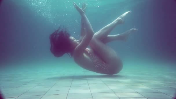 Piękna dziewczyna pod wodą / Piękna kobieta w błyszczącym stroju kąpielowym pozowanie pod wodą - filmy w zwolnionym tempie - Materiał filmowy, wideo