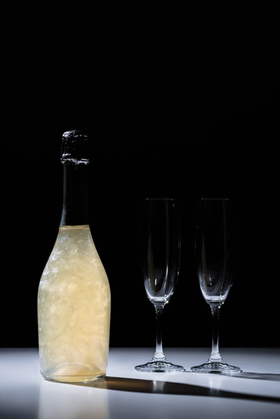 close up view of bottle of champagne and empty glasses on black background - Photo, Image