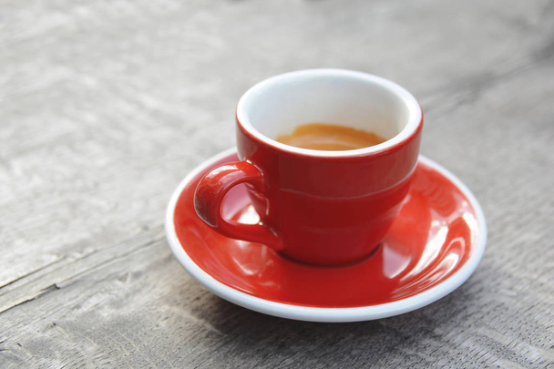 Rode espresso eerste koffie in de ochtend op houten kantine tafel - Foto, afbeelding
