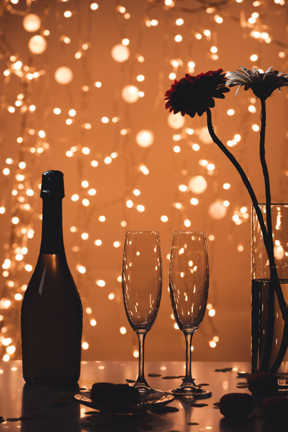 close up view of bottle of champagne, empty glasses and bouquet of flowers on tabletop - Foto, Bild