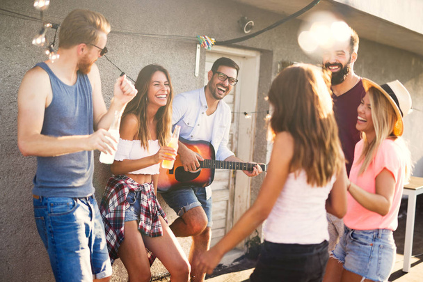 Groep van gelukkige jonge vrienden hebben feest op het dak - Foto, afbeelding