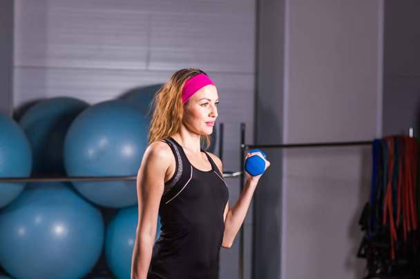 sport-, fitness-, opleiding- en geluk concept - sportieve vrouw handen met licht blauwe halters - Foto, afbeelding