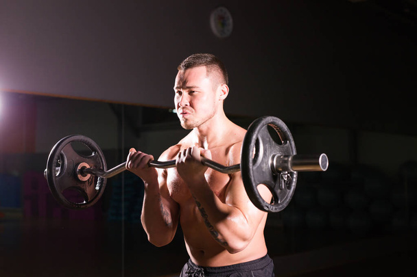 Komea urheilullinen mies, jolla on barbell. Vahva kehonrakentaja, jossa on kuusi pakkausta, täydelliset vatsalihakset, olkapäät, hauikset, triceps ja rinta
 - Valokuva, kuva