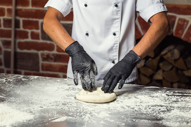 chef haciendo masa para pizza. Manos de hombre preparando pan. Concepto de panadería y pastelería
 - Foto, imagen