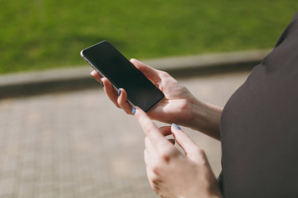 Nahaufnahme von Frauenhänden, die Handy, Smartphone mit leerem Bildschirm im Stadtpark im Freien halten und benutzen. Technologie, Kommunikationskonzept - Foto, Bild