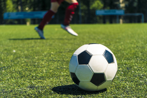 Από πυροβολισμό εστίαση από μπάλες ποδοσφαίρου και τα πόδια των παικτών ποδοσφαίρου κατά τη διάρκεια μιας προπόνησης ποδοσφαίρου σε γήπεδο πράσινο φυσικό ποδοσφαίρου. - Φωτογραφία, εικόνα