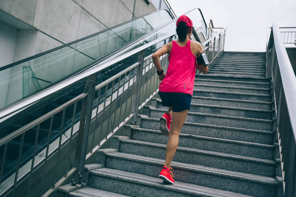 Young woman runner sportswoman climbing up city stairs jogging and running in urban training workout - Foto, Bild