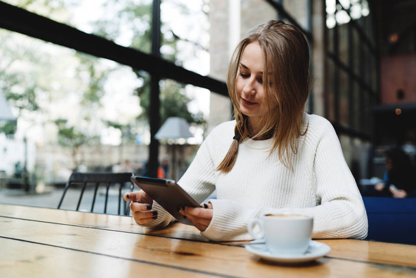 Beyaz kadın arkadaşı modern bir kafede için beklenirken bilgi online dijital tablet arama. İnternette haber okurken taşınabilir pc kullanarak genç iş kadını - Fotoğraf, Görsel