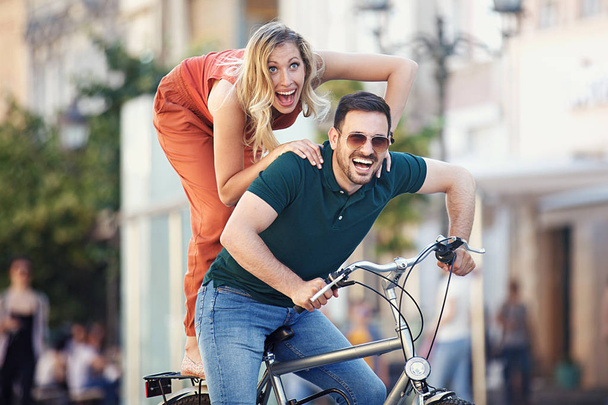Portrait of happy young couple riding a bike in the city. - Zdjęcie, obraz
