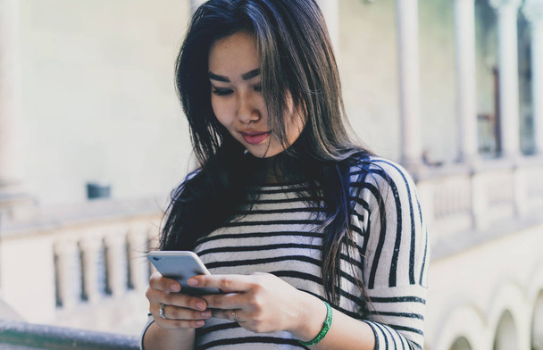 Smartphone ekrana bakarak uzun siyah saçlı bir güzel model bak Asya kadın fotoğrafı  - Fotoğraf, Görsel