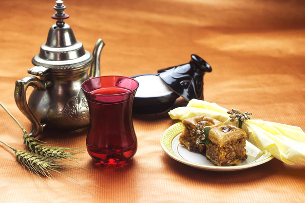 kotitekoinen arabialainen jälkiruoka baklava poltetulla maapähkinällä ja teekannulla ja sokerilla koristeltu vihreä piikki ramadanille
 - Valokuva, kuva