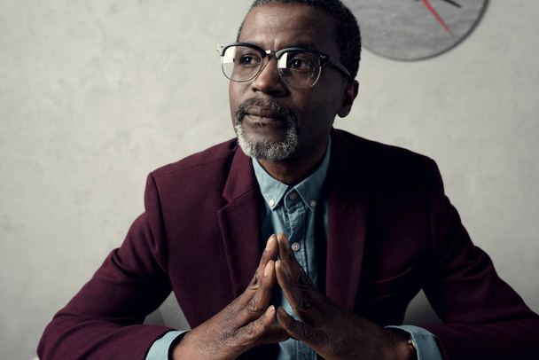 retrato de hombre afroamericano maduro pensativo en gafas y chaqueta de color burdeos
 - Foto, imagen