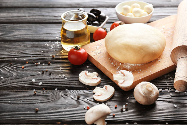 Wooden board with raw dough  and ingredients for pizza on table - Zdjęcie, obraz