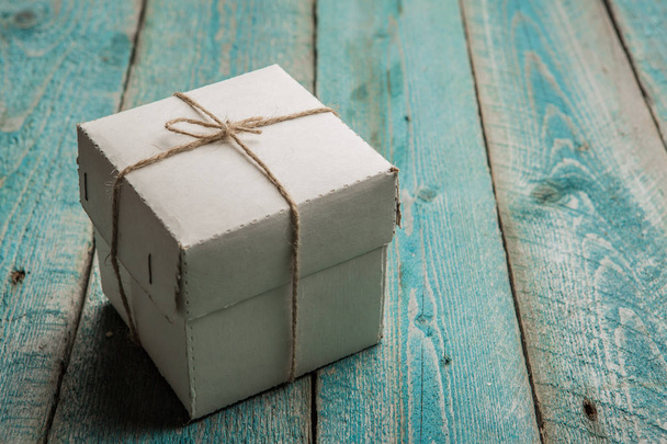 Single cardboard gift box tied with twine on wooden table - 写真・画像