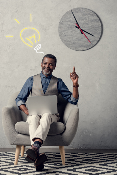executive african american businessman with laptop having idea and pointing up, with light bulb sign - 写真・画像