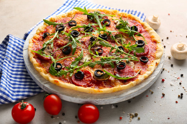 Houten plank met lekkere pizza op een grijze achtergrond - Foto, afbeelding