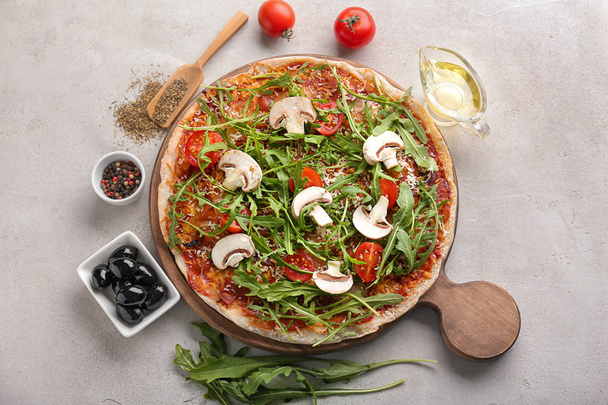 Houten plank met lekkere pizza op een grijze achtergrond - Foto, afbeelding