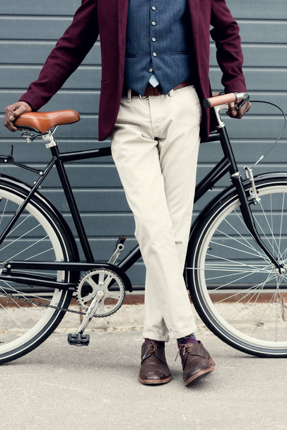 low section view of stylish man in burgundy jacket standing with bicycle - Photo, Image