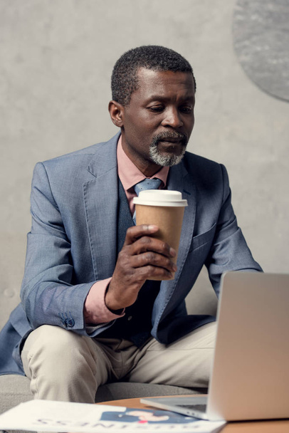 middle aged african american businessman in blue jacket with coffee and laptop - Photo, Image