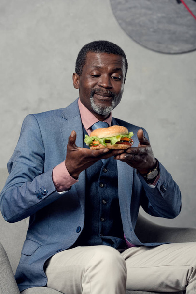 happy middle aged african american businessman with hamburger - Фото, зображення