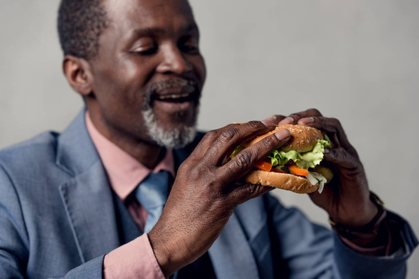 hombre afroamericano de mediana edad con hamburguesa
 - Foto, imagen