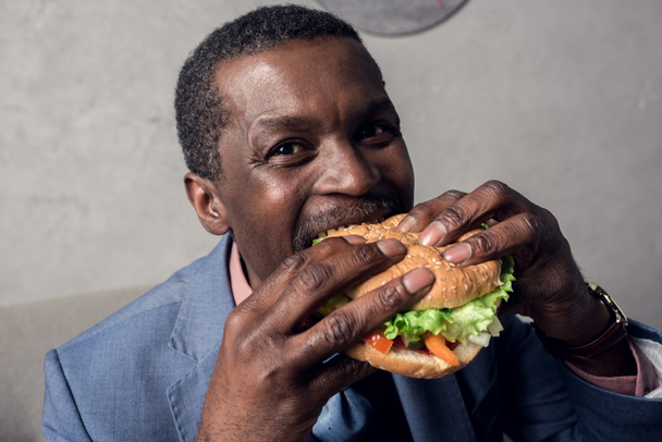 hungry african american man eating hamburger - Foto, Bild