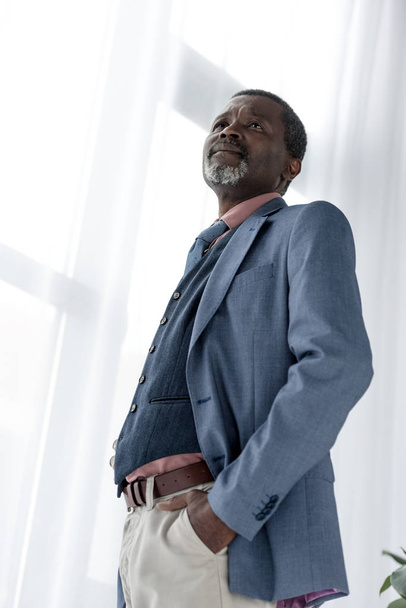 Onderaanzicht van volwassen Afrikaanse Amerikaanse man in blauw jasje - Foto, afbeelding