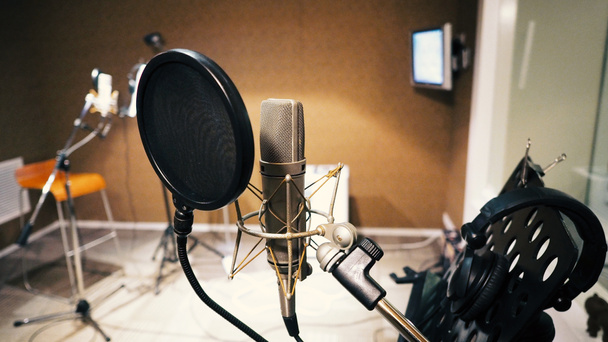 Микрофон с поп-фильтром и ударной установкой анти-вибрации и ноты стенд и штатив в музыкальной партитуре студии производства
 - Фото, изображение