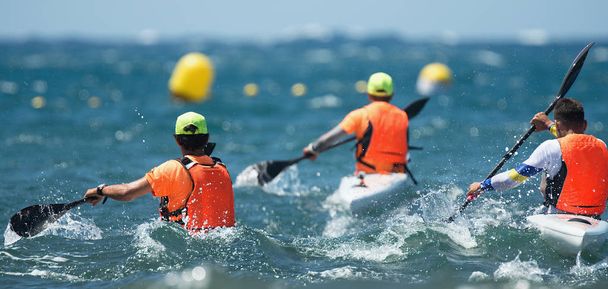 I paddlers corrono i loro sci da surf da kayak oceanici attraverso onde rotte
 - Foto, immagini