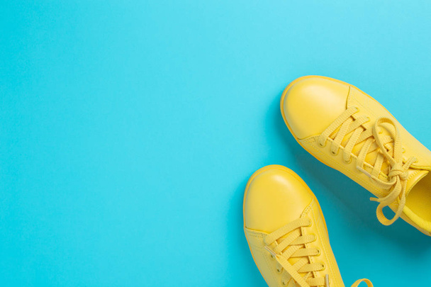 Pair of yellow shoes on blue background. - Photo, Image