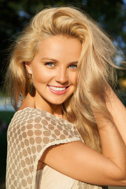 Closeup portrait of smiling blonde girl keeping her hair with ha - Foto, Imagen