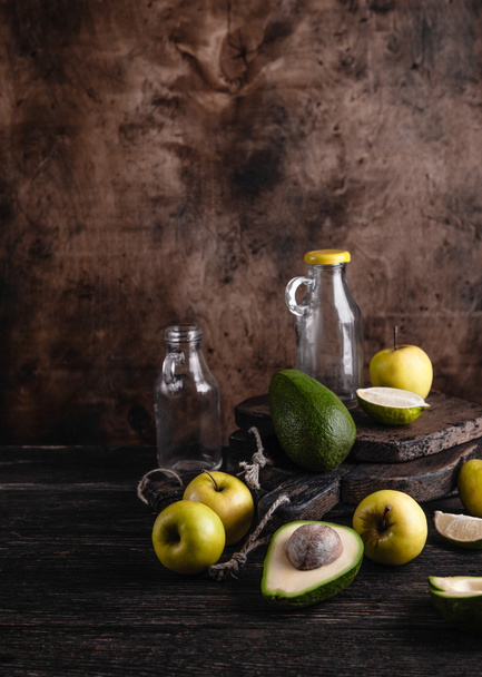 Glass bottles and fruit ingredients for smoothie on rustic wooden board - Foto, afbeelding