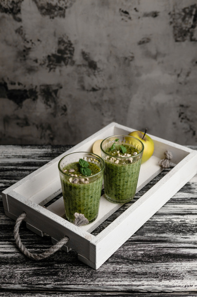 Batido verde sano fresco en vasos en bandeja rústica
 - Foto, imagen