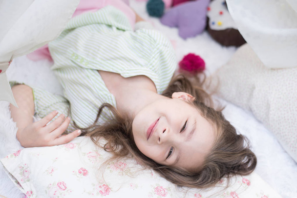 Чарівна маленька дівчинка прокинулася в ліжку. Чарівна маленька дівчинка спить у ліжку зі своєю іграшкою
. - Фото, зображення