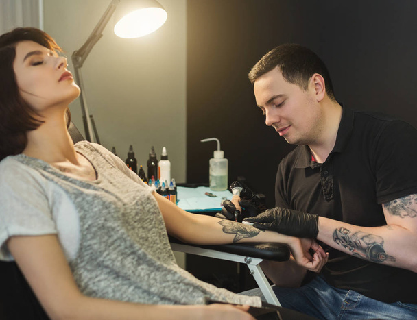 Doloroso proceso de tatuaje corporal, maestro trabajando en el estudio
 - Foto, Imagen
